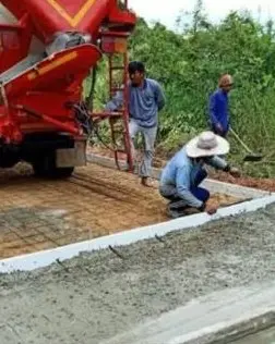 Crew finishing a concrete access road beside a mixer truck