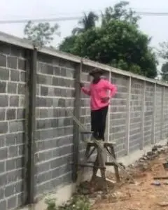 Worker rendering a concrete-block boundary wall
