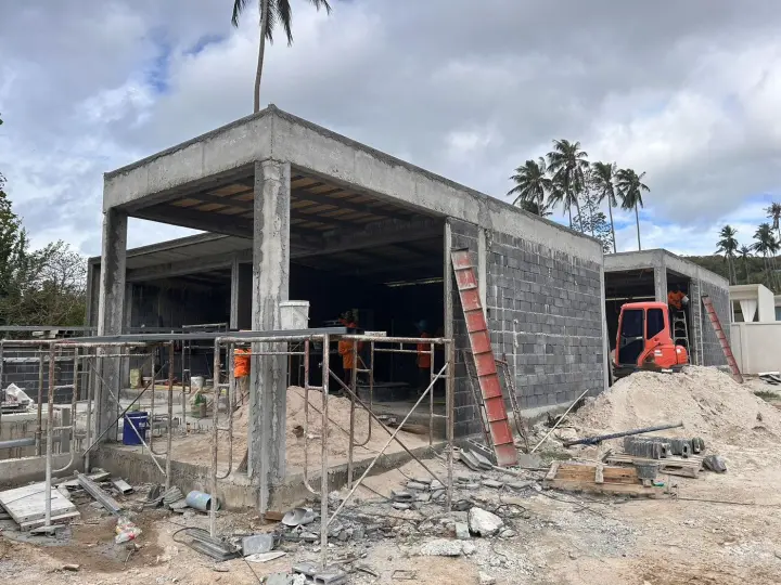Concrete frame and block walls with an excavator on site