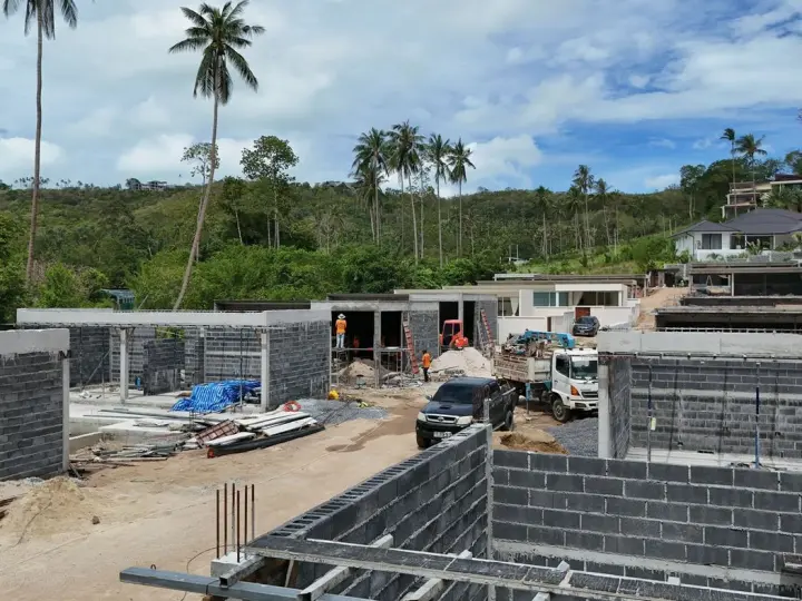 Roofed villas behind a row of new block walls