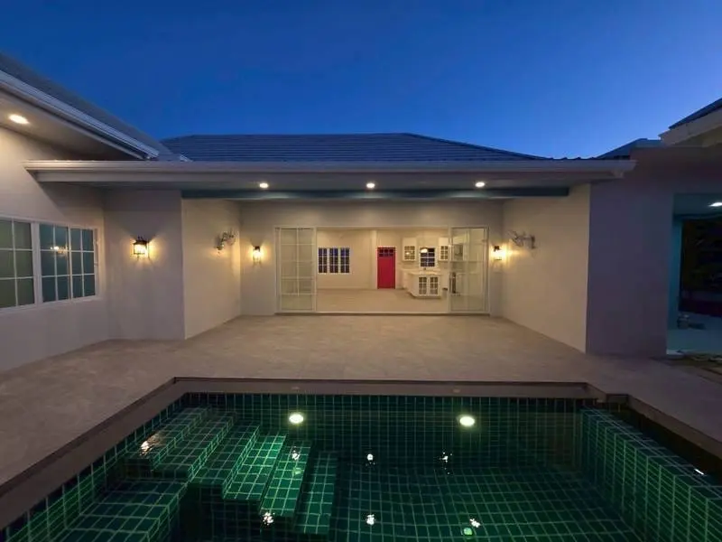 The Maenam pool villa at dusk, lit terrace and green-tiled pool